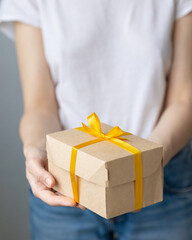 woman holding kraft cardboard boxes with yellow bow or ribbon, food or clothing delivery, modern ways to buy food with delivery, online store with home delivery, women's hands holding boxes of food or