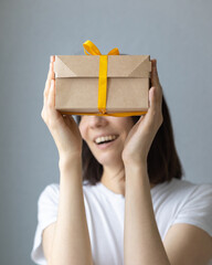 Fototapeta na wymiar woman holding kraft cardboard boxes with yellow bow or ribbon, food or clothing delivery, modern ways to buy food with delivery, online store with home delivery, women's hands holding boxes of food or