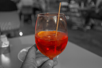 Close-up of hand holding a glass of spritz with color isolation effect, Vittorio Veneto, Italy