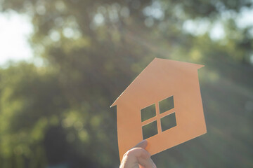 Paper mock-up of a house in the rays of the sun. Get the long-awaited housing, apartment, house.