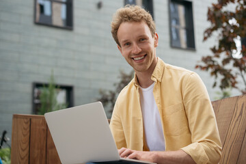 Young successful freelancer copywriter typing, planning project at workplace.  Smiling handsome computer programmer using laptop working online. Portrait of university student studying, education