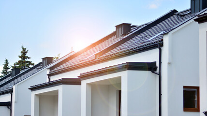New single family house in a new development area.  Residential home with modern facade. Rays of the sun in the background.