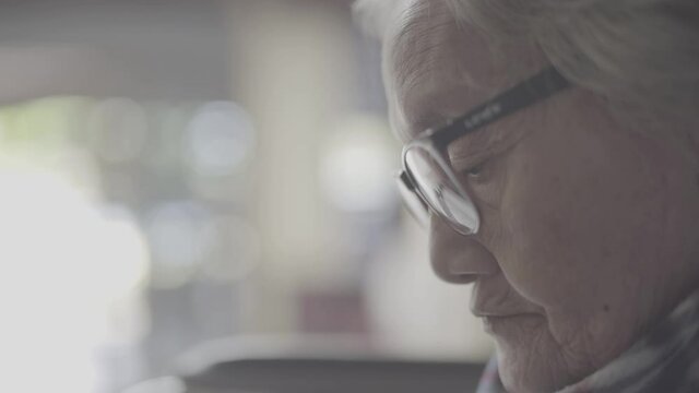 An elderly woman sitting on a wheelchair zooming in close up