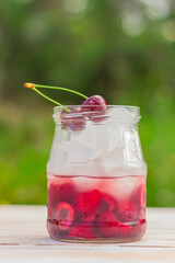 cherry cocktail with ice close-up on the table in the garden. detox infused water. summer refreshing drink.