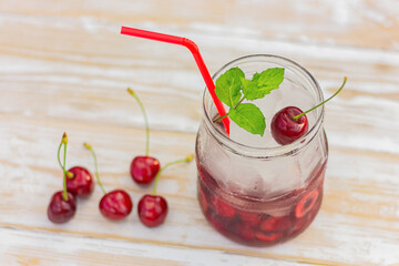 refreshing summer sweet cherry cocktail with ice and mint on white wooden table
