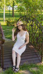 Fototapeta premium girl in a straw hat and a sundress on the background of spring and summer nature