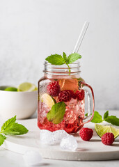 Cold summer refreshing mojito cocktail with raspberries mint and lime in a glass mason jar. Copy space.