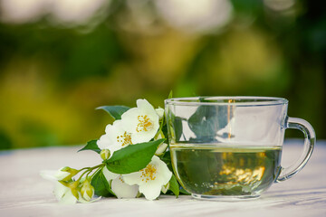 Philadelphus or garden jasmine flowers, healthy herbal tea cup of hot tea. Romantic dinner with therapeutic fragrant tea.