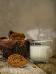 A beautiful still life of tasty and healthy products. Black bread in a basket on a brown napkin, milk in a jug and glass. Close-up. Light background. There are no people in the photo. Color image.