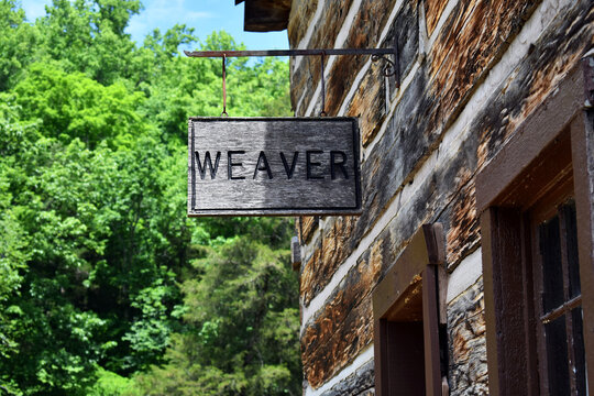 Wooden Weaver Sign Hanging Outside A Log Cabin