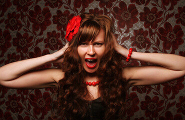 Obraz na płótnie Canvas Frustrated and angry brunette woman with red flower in hair screaming and grabs his head.