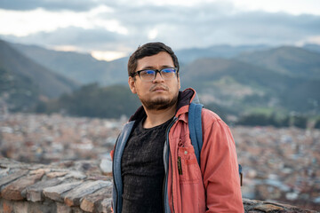 Young Latin American man with landscape in the background and lost eyes, broken heart, he feels bad, thinking about his worries, he does not know his future.