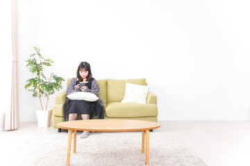 家でスマートフォンを使う若い女性