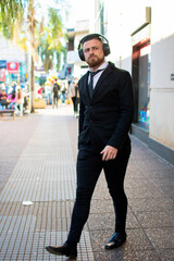 retrato de hombre caucásico con barba  formal con auriculares caminando por la ciudad 