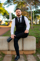 Obraz premium Hombre joven caucásico vistiendo ropa formal empresarial con una mirada seria sentado al aire libre