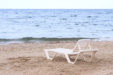 Fototapeta na wymiar a lonely chaise longue on a sandy beach by the sea. on a bright sunny day. the sea with waves.