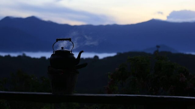 Nearby, boil an old kettle on fire with a stove. Charcoal behind is a beautiful mountain view,before the sun rises in low light
