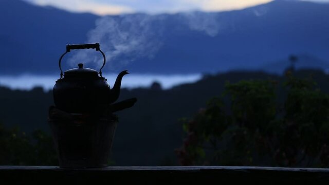 Nearby, boil an old kettle on fire with a stove. Charcoal behind is a beautiful mountain view,before the sun rises in low light