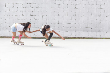 Two friends in shorts, white t-shirt and long socks skate fun on roller skates on a summer morning