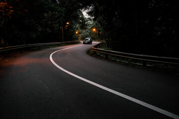 A less busy road with a moody environment having a car in motion
