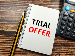 Business concept. Text TRIAL OFFER on notebook with pencil and calculator on wooden table...