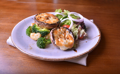 vegetarian grilled big fresh mushroom with bake cheese porbettolo and broccoli vegetables wood table western vegetarian menu