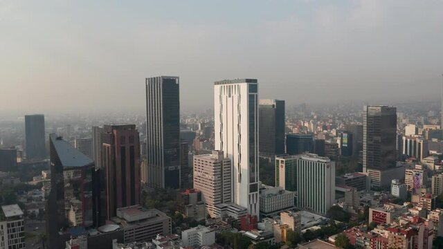 Panorama curve shot of downtown. Flying towards tall office buildings. Limited visibility due to air pollution. Mexico City, Mexico.