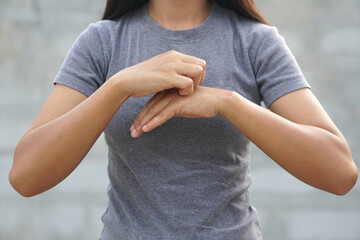 Woman scratching arm from itching on light gray background. Cause of itchy skin include insect...