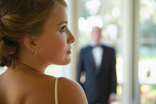 Profile of Bride waiting for her big day, father of the bride seen out of focus in background 