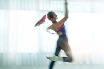 Abstract image of dancer practicing her performance in dance studio near large window, blury image