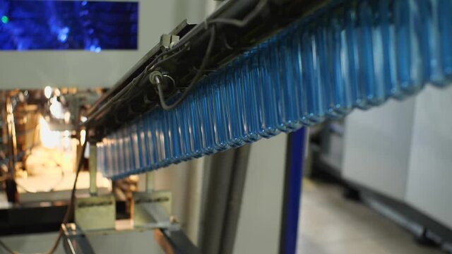 Blue plastic preforms are sent along the conveyor to the bottle blowing machine. Plant for the production of drinking and mineral water