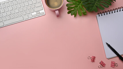 Woman space with coffee cup, notebook and keyboard on pink background.