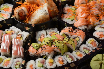 Set of sushi rolls  on a black plastic platter decorated with soy sauce and spices. Ready for delivery © Natalia Hanin