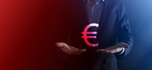 Businessman holds money coin icons EUR or Euro on dark tone background..Growing money concept for business investment and finance