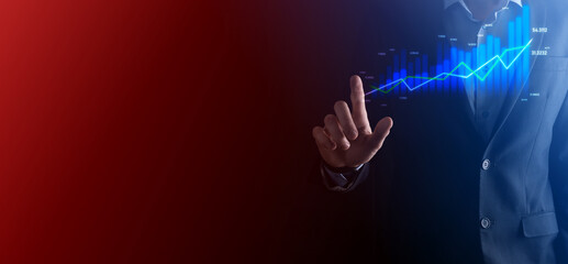 Fototapeta premium Business man holding holographic graphs and stock market statistics gain profits. Concept of growth planning and business strategy. Display of good economy form digital screen.