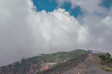 horizontal shot of the viewpoint to the main crater surrounded with little vegetation rocky and sandy terrain with blue sky in the Irazu Volcano National Park - Cartago - Costa Rica - Central America