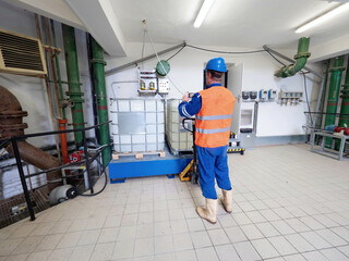 Working man handles a pallet truck and a chemical material tank.