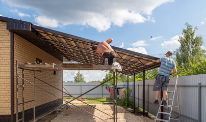 Workers install a metal shed on a wooden frame.