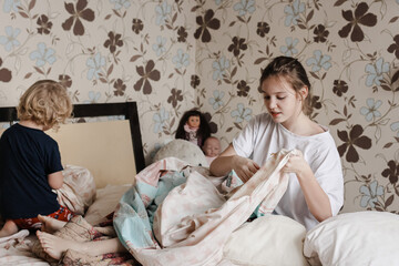 Children helping with cleaning the house, removing bed linen, doing chores. Lifestyle, brother and sister, family.