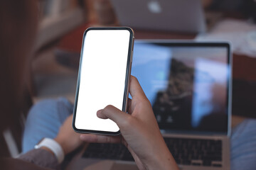 Cell phone mockup image blank white screen.  Woman hand holding, using mobile phone in coffee shop, close up