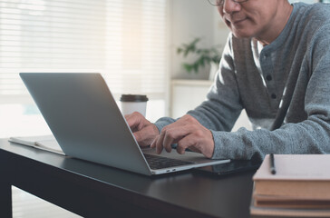 Asian casual business man typing on laptop computer working from home