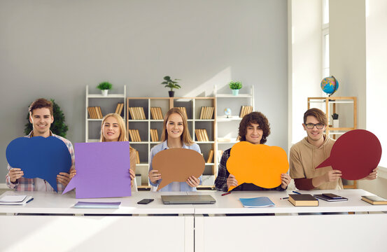 Teenager Student Classmates Friends Group Holding Free Space Paper Speech Bubbles Sitting At Shared Desk. Online Communication Chat Or Forum, Opinion And Ideas Exchange And Feedback