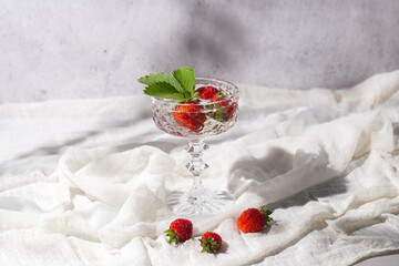 Fresh juicy strawberries in a glass on a light fabric background