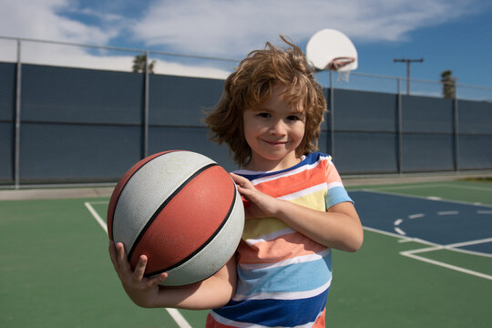 Cute little boy holding a basket ball trying make a score. Sport for kids.