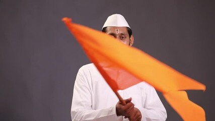 Young indian man (pilgrim) in traditional wear and waving religious flag.