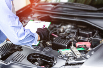 Technician check list problem of car in white paper with engine room service concept in workshop