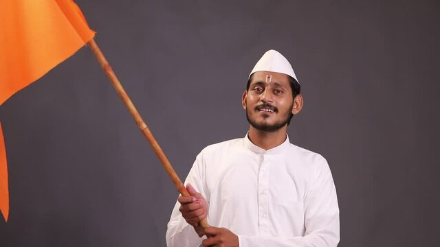 Young indian man (pilgrim) in traditional wear and waving religious flag.