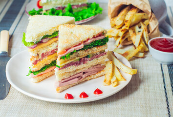 club sandwich with ham, tomatoes, lettuce and mayonnaise between slices of  bread 