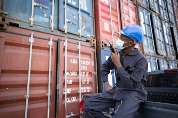 Fototapeta na wymiar Black Inspector with Protect Mask Inspecting the Containers at the Port