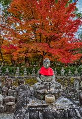  Stone statue of Buddha with autumn colored tree in  Adashino Nenbutsuji temple in Arashiyama.  Kyoto, Japan.